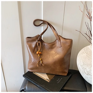 Detail of retro brown leather tote bag with vintage texture and wooden bead pendant