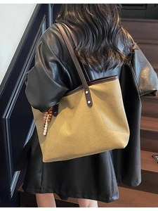 Fashionable khaki canvas tote bag with brown trim and beads in a lifestyle setting