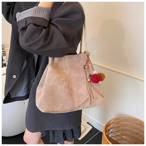 Detail of khaki suede tote bag with retro tassel charm and elegant vertical stitching
