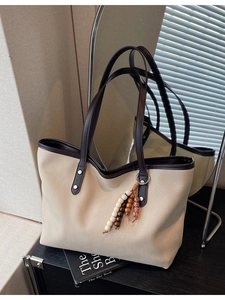Minimalist canvas tote bag with brown leather trim and colorful bead charm for commuting