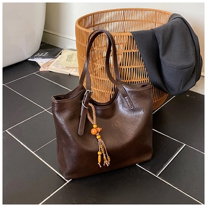 Detail of dark brown leather tote bag with colorful bohemian beaded tassel charm