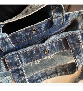 Detail of vintage denim tote bag featuring premium metal snap closure and denim texture