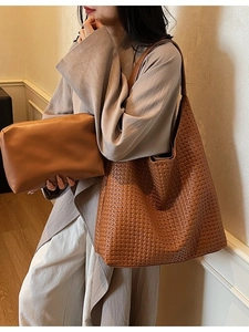 Brown woven leather tote bag with matching pouch shown in a stylish fashion lifestyle setting