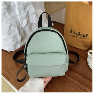 Detailed close-up of a mint green mini backpack on a rustic wooden table with tea set