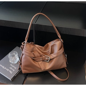 Detail of brown litchi pattern leather tote with metal buckle on black display stand