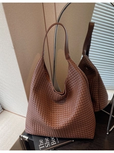 Large dark brown woven leather tote bag with shoulder strap in a minimalist setting