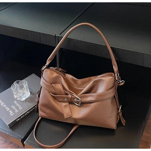 Detail view of large brown pebble leather tote bag with silver buckle and shoulder strap