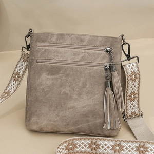 Macro detail of khaki faux leather shoulder bag featuring metallic chain tassel zippers