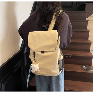 Detailed back view of a beige nylon backpack with a cute white plush lamb pendant