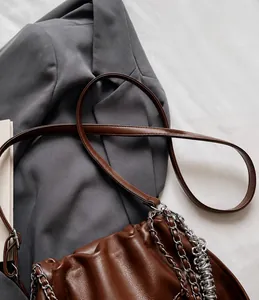 Detailed shot of dark brown pleated bucket bag with silver chain and long leather strap
