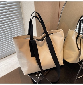 Detail of canvas tote bag with contrast black straps and striped lining in soft natural light