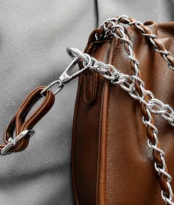 Detail of dark brown leather bag with silver metal lobster clasp and chain strap