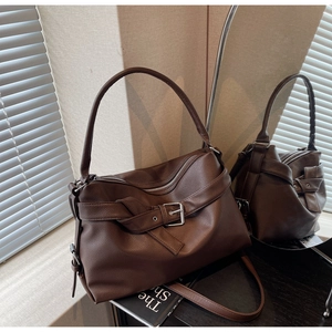 Close-up of the dark brown lychee leather texture and silver buckle on the tote bag