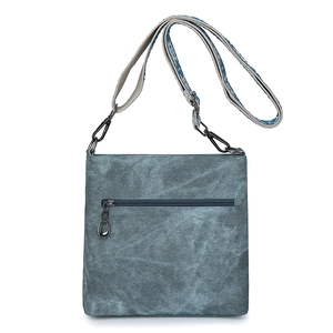 Detail view of denim crossbody bag with back zipper pocket and patterned woven strap