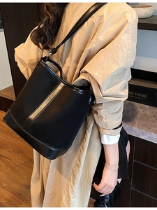 Minimalist black leather bucket bag with vertical trim shown on model in modern setting
