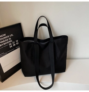 Detail of black canvas tote bag showing dual handles and black-and-white striped lining