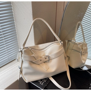 Detailed view of the off-white lychee grain leather texture and metallic buckle of the tote bag