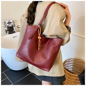 Detail of burgundy faux leather tote bag with wooden bead tassel and long shoulder strap
