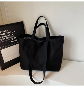 Detail of black canvas tote bag showing reinforced handles and striped lining