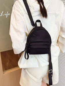 Minimalist black lightweight nylon backpack for women shown on a model in a casual setting