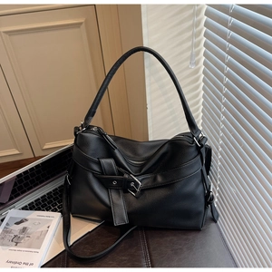 Detailed view of black pebbled leather tote bag with buckle detail on a leather seat