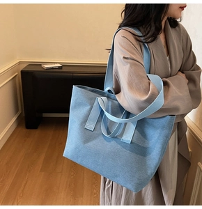 Detail of blue large canvas tote bag with double straps shown in a lifestyle indoor setting