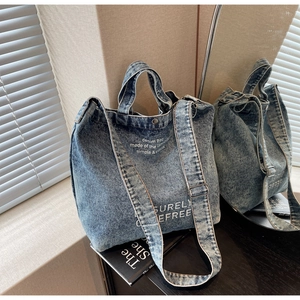 Detail of blue denim tote bag with surely carefree print shown in a mirror reflection