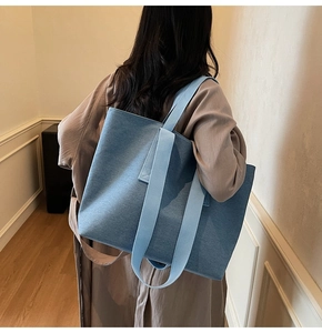 Detail of blue canvas tote bag showing textured fabric and wide shoulder strap