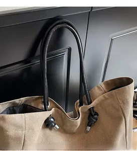 Detail of durable brown canvas tote with black leather rope handle and silver grommets