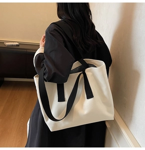 Minimalist cream canvas tote bag with black wide straps and blue striped lining detail