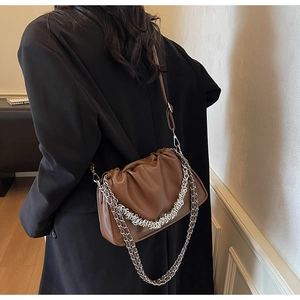 Close-up of brown pleated pouch bag with chunky silver chain and leather strap details