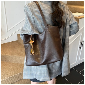 Detail of dark brown leather tote bag with wooden bead and leather tassel charm