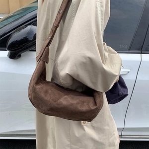 Street style shot of a dark brown suede hobo bag with a wide adjustable shoulder strap