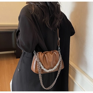 Detail of brown pleated bucket bag with silver metal chain and leather shoulder strap