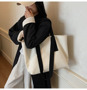 Minimalist cream canvas tote bag with contrast black shoulder straps on model