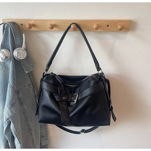 Detail of black pebbled leather tote bag with silver buckle and cross strap design