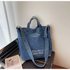 Detailed view of the large denim tote bag with printed text on leather stool