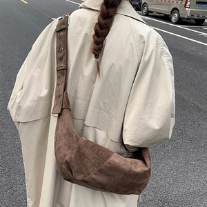 Street style view of a large brown suede crescent bag worn by a model in the city