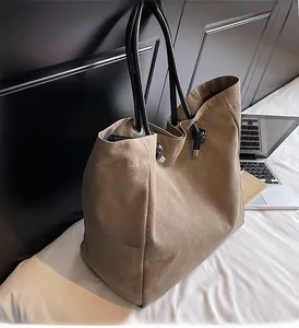 Khaki canvas tote bag with black rope handles shown in a cozy home office setting