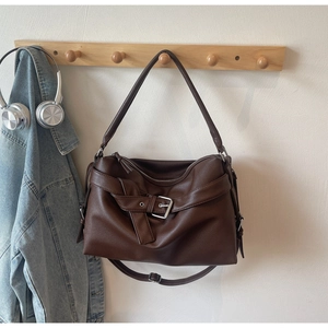 Detail view of dark brown pebbled leather tote with belt buckle and dual straps