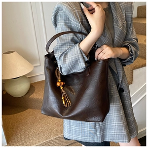 Macro detail of dark brown leather tote bag with vintage beaded tassel and shoulder strap