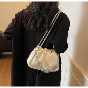 Close-up of cream pleated cloud bag with chunky silver chain and leather texture