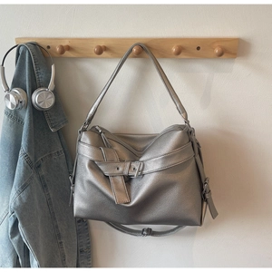 Silver tote bag in matte pebbled leather hanging with headphones on a wooden hook