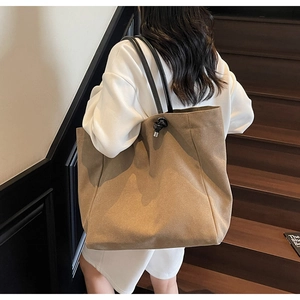 Detail view of khaki canvas tote bag with black straps and drawstring on a model