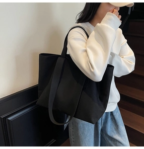 Close-up of black canvas tote bag with wide straps and spacious interior for commuting