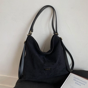 Close-up of black hobo bag with suede texture, gold buckles, and leather fashion label