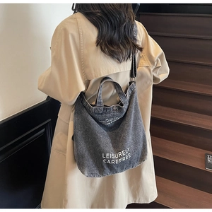 Detail of dark grey washed denim tote bag with leisurely carefree print on wide shoulder strap