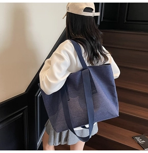Rear view of model wearing a large blue denim tote bag on wide shoulder straps