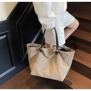 Minimalist large khaki tote bag with knot handle detail held by model on stairs