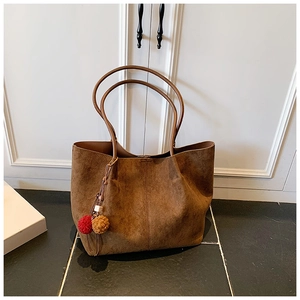 Brown suede tote bag with long handles and a dual-color decorative pompom charm